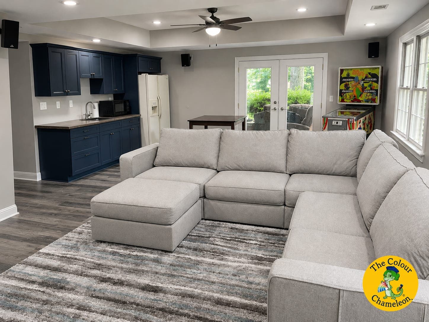 The same basement in light gray with navy cabinetry and a gray sectional