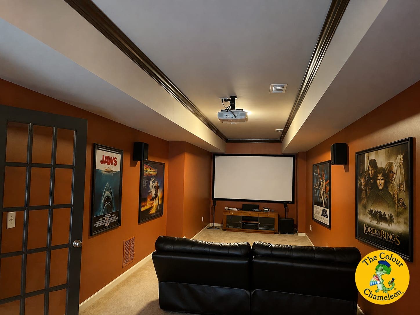 The same room in burnt orange with framed film posters either side of the screen