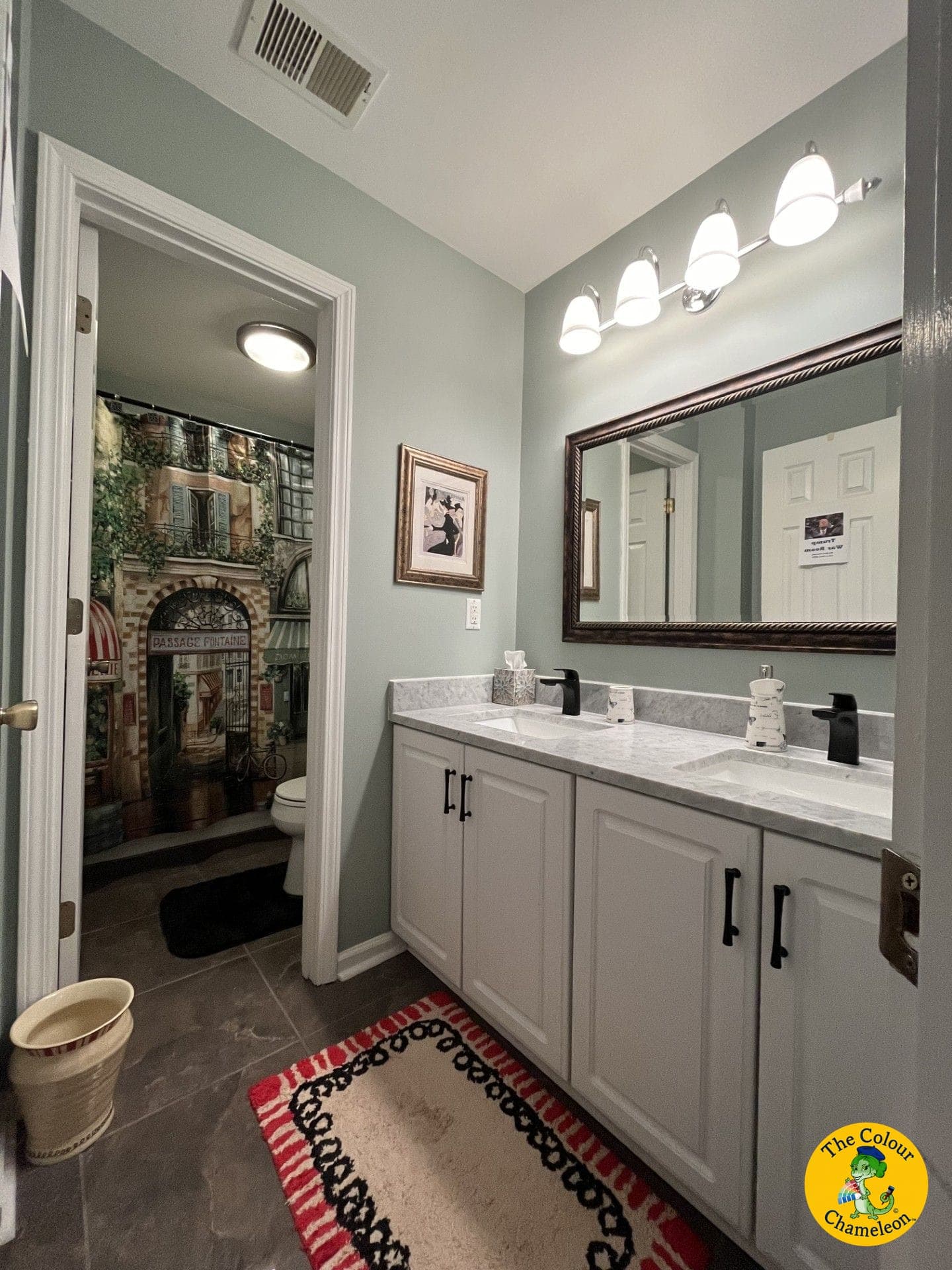 The same bathroom in soft blue-green with double sinks, black fixtures and a Parisian street-scene curtain