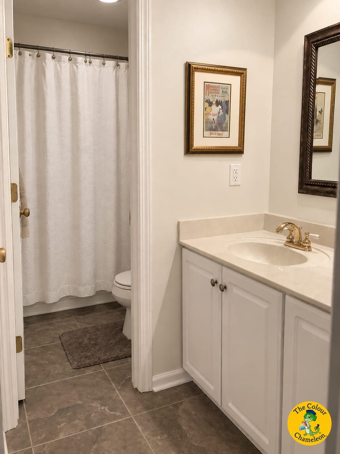 A bathroom in flat cream with a single sink, gold fixtures and a white vanity