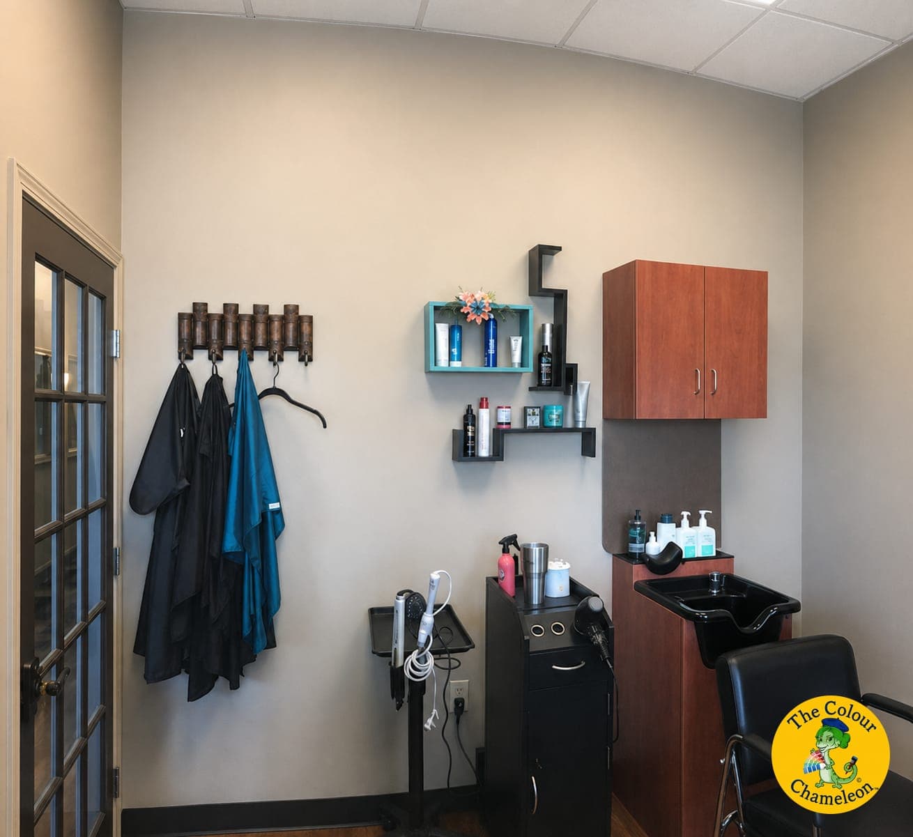 A salon suite with beige walls, a cherry wall cabinet and a black shampoo bowl