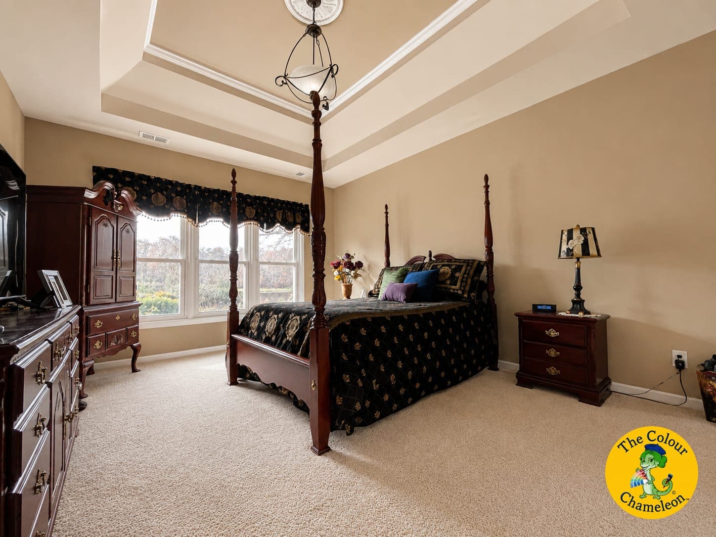 A bedroom in gold walls with a dark four-poster bed and black bedding