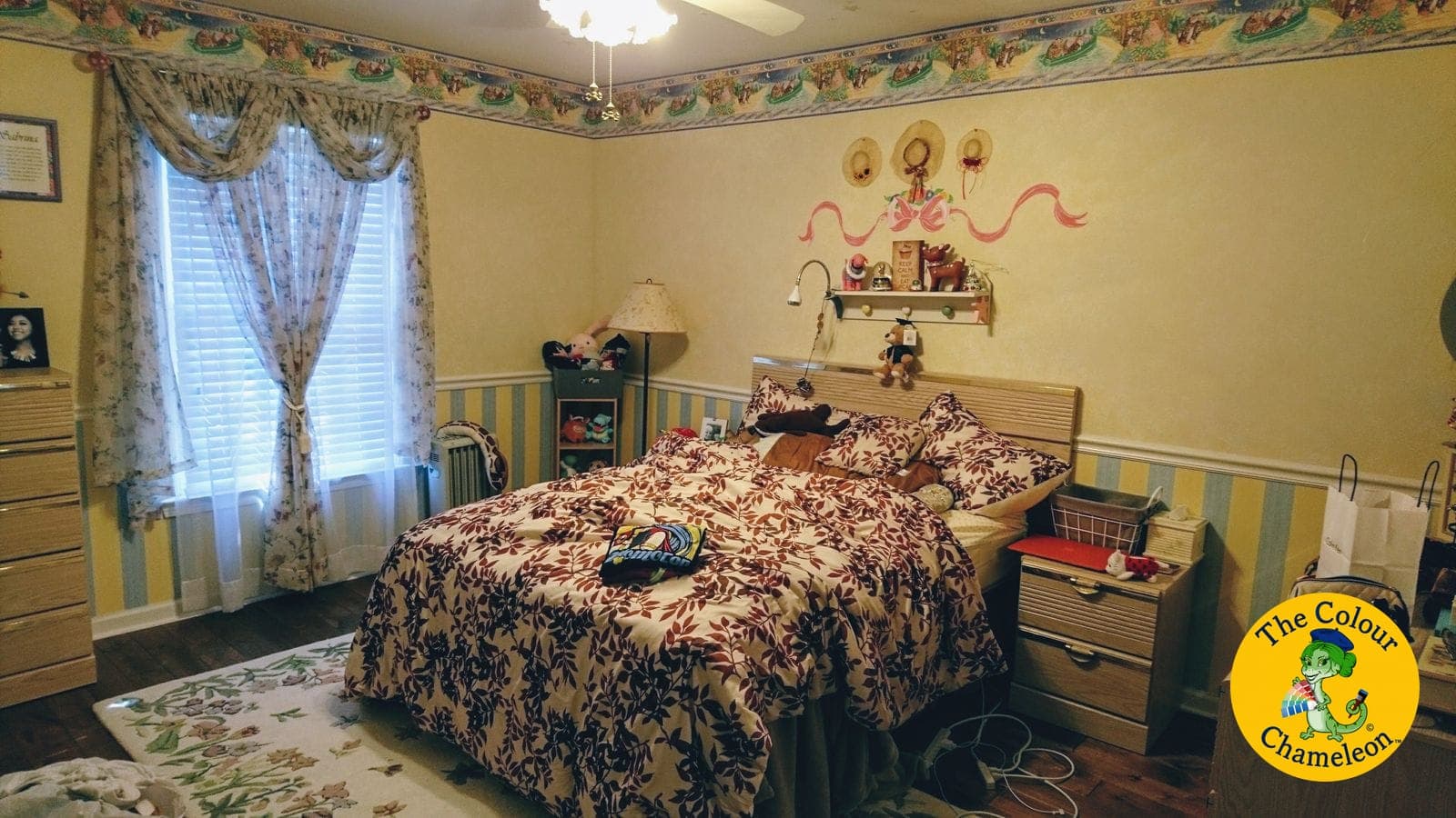 A bedroom in yellow with a wallpaper border and blue-and-yellow striped wainscot