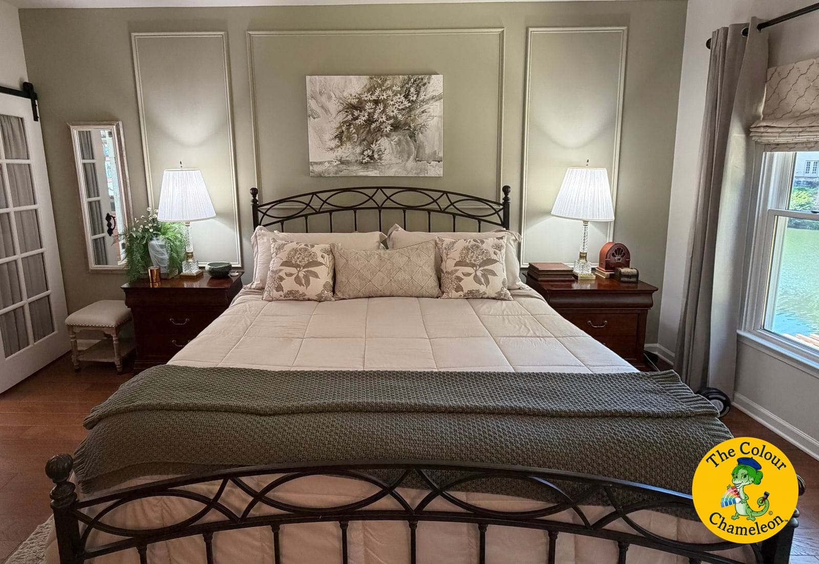 The same bedroom in soft sage green with white picture-frame molding behind the bed