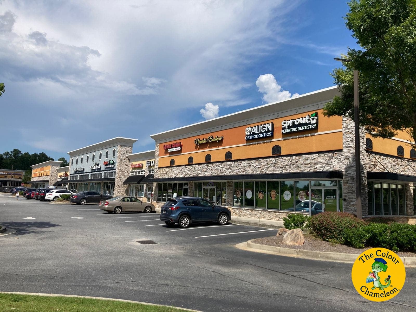 A shopping center with a bright orange upper facade