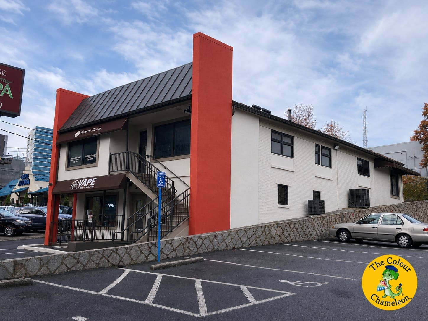 The same building in white with red-orange pilasters and a black roof and awning