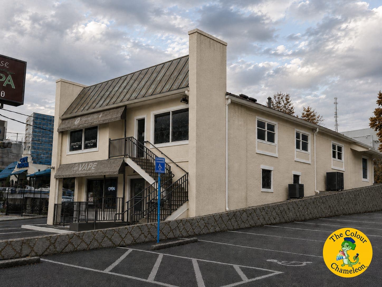 A two-story commercial building in flat cream stucco with a gray metal roof