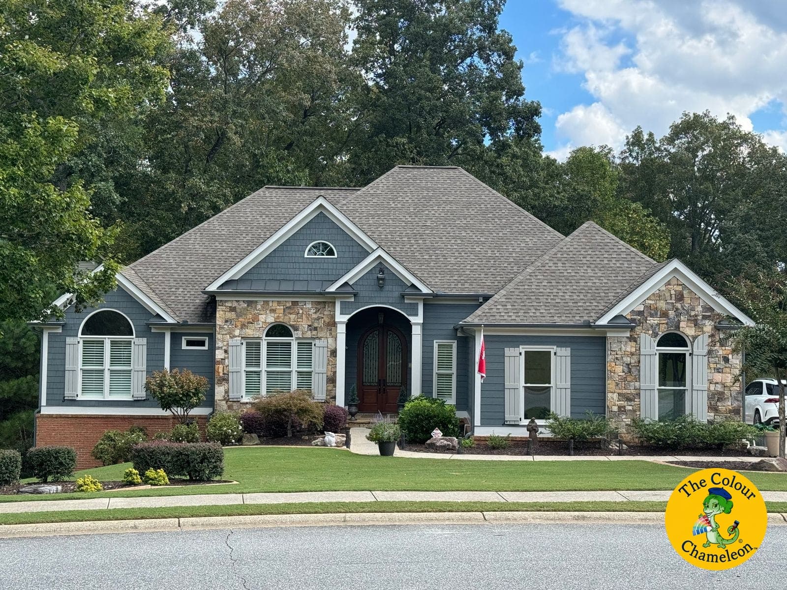 The same ranch in a single slate blue-gray siding color with cream shutters, the stonework left as it was