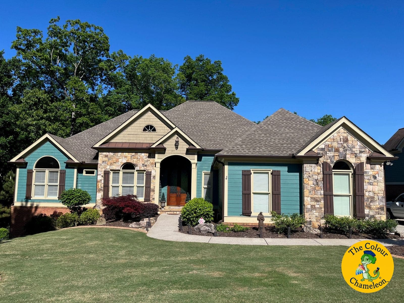 A stone-and-siding ranch in teal with butter-yellow trim and reddish-brown shutters