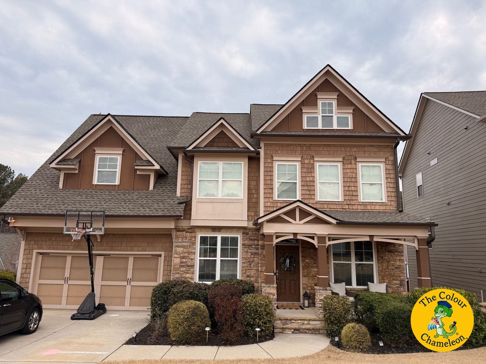 A two-story house in brown siding and shakes with a matching brown garage door