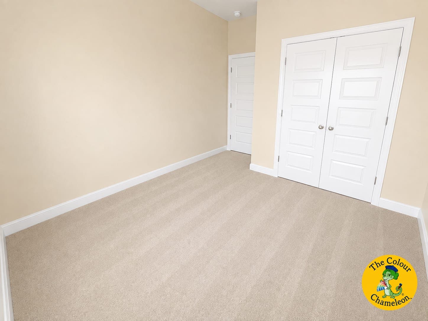 An empty bedroom with flat beige walls, white doors and pale carpet