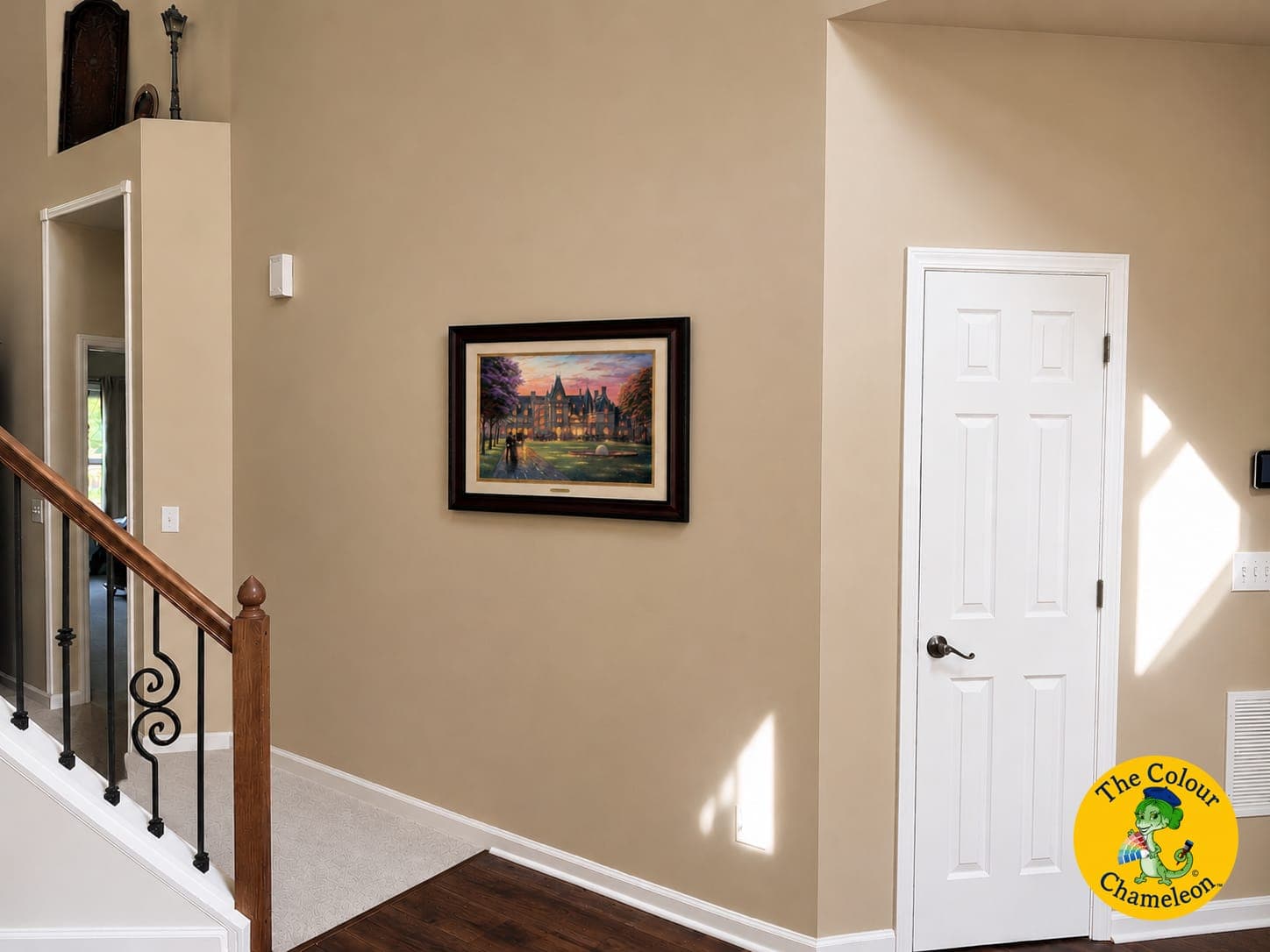 A two-story entry hall in warm gold-tan with a single framed painting