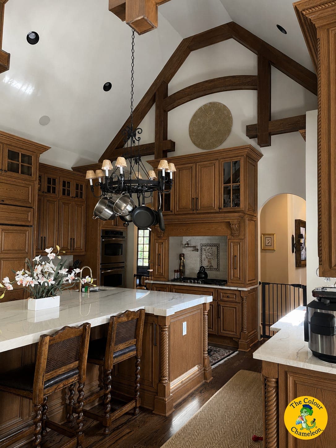 A kitchen of stained wood cabinets and a matching wood island under a beamed vaulted ceiling