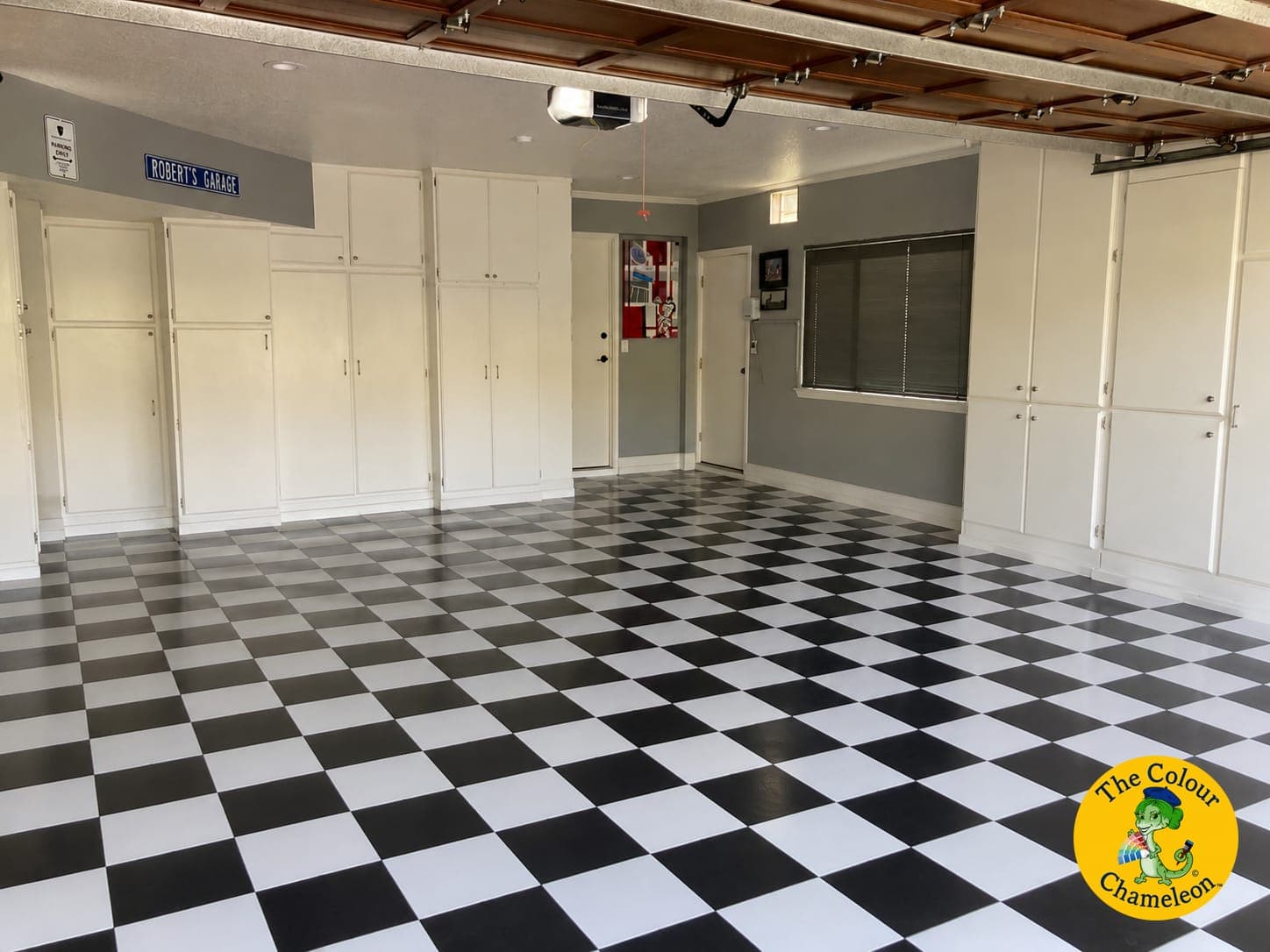 A garage with cream cabinets, gray walls and a black-and-white checkered floor