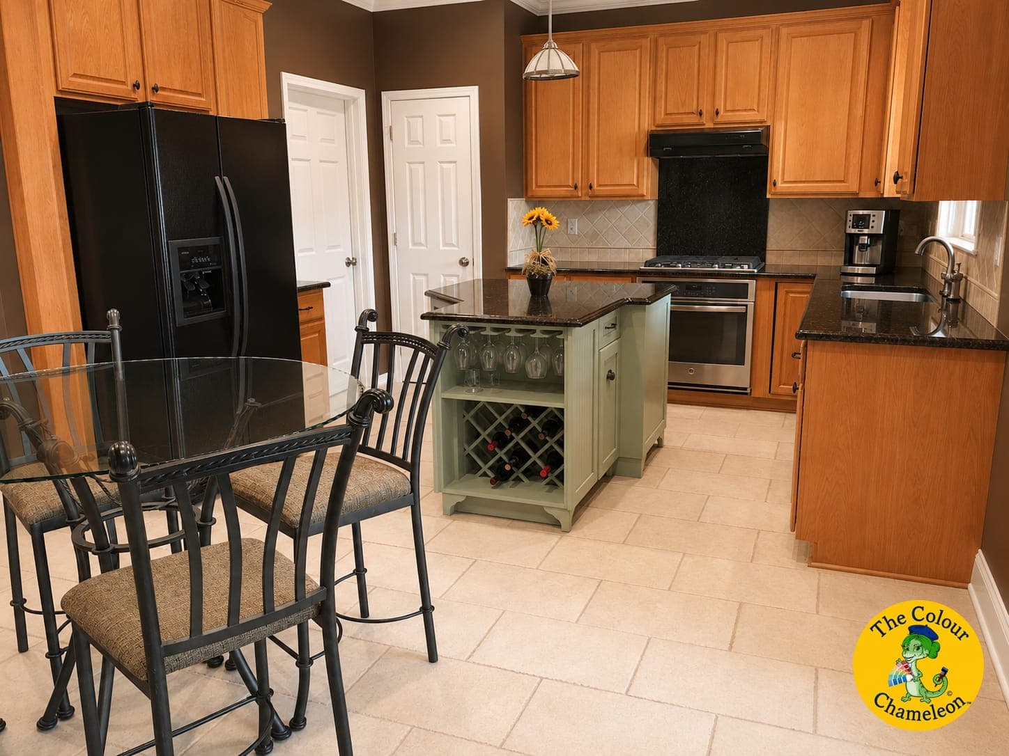 A kitchen with maple cabinets, brown walls, a black refrigerator and a sage-green island