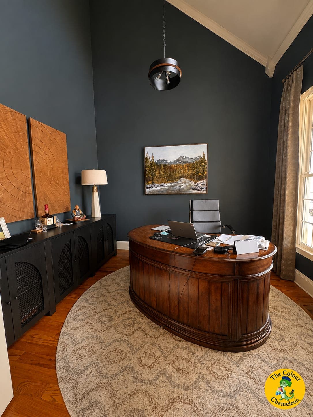 The same room in deep navy with a curved wooden desk on a round rug